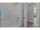 Clean shower in a bathroom with white tile and fixtures is shown with a view into the next room at 975 Mt Moriah Church Rd, China Grove, NC 28023