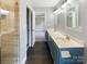 Bright bathroom featuring a double vanity, modern lighting, and a glass-enclosed shower at 10406 Baskerville Ave, Charlotte, NC 28269