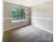 Cozy bedroom with neutral carpet and a large window offering views of the green neighborhood at 10406 Baskerville Ave, Charlotte, NC 28269