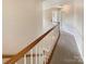 Hallway featuring a wood railing, neutral carpet, and bright natural light from nearby rooms at 10406 Baskerville Ave, Charlotte, NC 28269