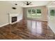 Spacious living room featuring hardwood floors, a fireplace, and large windows, providing plenty of natural light at 10406 Baskerville Ave, Charlotte, NC 28269