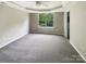 Clean, vacant main bedroom with ceiling fan, ensuite bathroom, carpet, and a large window at 10406 Baskerville Ave, Charlotte, NC 28269