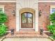 Elegant arched front door framed by brick facade, stone accents, and decorative lighting at 11321 James Jack Ln, Charlotte, NC 28277