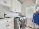 Functional laundry room with modern washer/dryer, custom cabinets, and a window for natural light at 11321 James Jack Ln, Charlotte, NC 28277