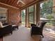 Cozy sunroom with brick accents, comfortable seating, and large windows showcasing the outdoor landscape at 11321 James Jack Ln, Charlotte, NC 28277