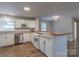 Well-lit kitchen with wood-look floors, stainless steel dishwasher and breakfast bar with open access to the living area at 133 Pheasant Run Rd, Troutman, NC 28166
