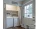 Bright laundry area featuring a white washer and dryer set with shelving and natural light from the back door at 133 Pheasant Run Rd, Troutman, NC 28166