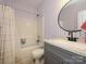 Stylish bathroom featuring patterned wallpaper, modern vanity, a sleek round mirror, and a shower-tub combination at 14336 Northridge Dr, Charlotte, NC 28269