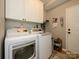 Efficient laundry room with white cabinetry, modern washer and dryer, and tile flooring, optimizing functionality and storage at 14336 Northridge Dr, Charlotte, NC 28269