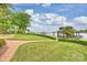 Lush backyard with manicured lawn, brick path, mature trees, and a view of the lake and dock at 16909 Jetton Rd, Cornelius, NC 28031