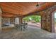 Spacious covered patio featuring a stone surround, wood ceiling, and open access to the backyard pool area at 16909 Jetton Rd, Cornelius, NC 28031
