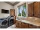 Well-equipped laundry room with wooden cabinets, granite countertop, sink, and modern washer and dryer units at 16909 Jetton Rd, Cornelius, NC 28031
