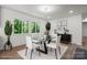 Elegant dining room featuring a glass table, white chairs, modern decor, and large windows with views of the outdoors at 218 Kingsway Cir, Charlotte, NC 28214