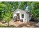 Charming single-story home with white brick exterior, surrounded by lush trees and mature landscaping at 218 Kingsway Cir, Charlotte, NC 28214
