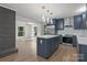Open kitchen with navy cabinets, stainless appliances, island, marble backsplash and modern lighting open to the living area at 218 Kingsway Cir, Charlotte, NC 28214