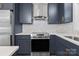 Close up shot of a modern kitchen featuring stainless steel appliances, navy cabinets, marble backsplash and white countertops at 218 Kingsway Cir, Charlotte, NC 28214