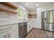 This kitchen features white cabinets, stainless steel appliances, wood shelving, and a farmhouse sink at 26056 Neptunes Lndg, Fort Mill, SC 29708