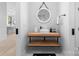 Contemporary bathroom showcasing a floating wood vanity with white vessel sink and unique round mirror at 2913 Lake Ave, Charlotte, NC 28208