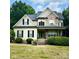 Inviting two-story home with a covered front porch, stone accents, manicured landscaping, and a vibrant green front door at 3320 Harvey Ln, Monroe, NC 28110