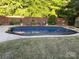 Backyard pool surrounded by a concrete patio, set against a wooden fence with landscaping and decorative elements at 3320 Harvey Ln, Monroe, NC 28110