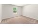 Empty bedroom with a window showing lots of light and neutral carpeting at 3334 Strong Box Ln, Gastonia, NC 28052