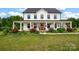 Charming two-story farmhouse with a welcoming wraparound porch and vibrant landscaping at 355 Cal Kennedy Rd, Cleveland, NC 27013