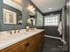 Bathroom featuring double sinks, white countertops, wooden vanity, and a walk-in shower with gray tile at 4315 Poplar Grove Dr, Charlotte, NC 28269