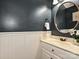 Elegant bathroom features white wainscoting, blue-gray walls, and a round mirror above the sink at 4315 Poplar Grove Dr, Charlotte, NC 28269