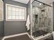 Modern bathroom featuring a glass-enclosed shower with gray tile, black hexagon floor tiles, and window at 4315 Poplar Grove Dr, Charlotte, NC 28269