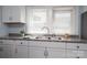 Close-up of a modern kitchen sink with white cabinets, countertops, and double windows at 520 E Maple Ave, Gastonia, NC 28054