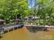 Lakefront backyard with a multi-level dock, sandy beach, and lush landscaping at 570 Blue Heron Rd, Salisbury, NC 28146