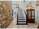 Elegant interior staircase featuring stone wall, dark banister, and light wood floors at 570 Blue Heron Rd, Salisbury, NC 28146