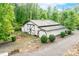 A beautiful white barn with a metal roof and black trim, surrounded by lush greenery and a gravel driveway at 707 Saint Cloud Dr, Statesville, NC 28625