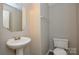 Half bathroom featuring pedestal sink, mirror, and a toilet at 7311 Fig Ln, Charlotte, NC 28215