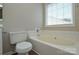 Bathroom featuring a bathtub with tile surround, toilet, and window at 7311 Fig Ln, Charlotte, NC 28215