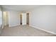This is a bright bedroom with neutral walls, plush carpet, and an open doorway to an ensuite bathroom at 7311 Fig Ln, Charlotte, NC 28215