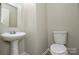 Cozy powder room with pedestal sink, toilet, and neutral color palette at 7711 Brisbane Ct, Charlotte, NC 28215
