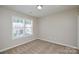 Carpeted bedroom with two bright windows and neutral-colored walls at 7711 Brisbane Ct, Charlotte, NC 28215