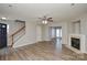 Open-concept living room with a fireplace, ceiling fan, and access to other areas of the home at 7711 Brisbane Ct, Charlotte, NC 28215