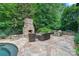 Outdoor space with stone patio, outdoor kitchen, fireplace, stone seat wall and manicured green space at 8534 Highgrove St, Charlotte, NC 28277