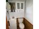 A compact bathroom with a white vanity and cabinet, a standard toilet, and paneled wainscoting at 947 Ravendale Dr, Charlotte, NC 28216