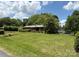 Spacious yard featuring a brick home with mature trees, lush greenery, and a detached garage at 947 Ravendale Dr, Charlotte, NC 28216