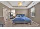 This bedroom features a tray ceiling, large windows, and a queen-sized bed with blue bedding at 9614 Turning Wheel Dr, Charlotte, NC 28214