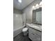 Well-lit bathroom with a modern granite vanity, framed mirror, tiled floors, and tub with shower at 1024 Short St, Salisbury, NC 28144