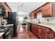 Traditional kitchen with cherry cabinets, granite countertops, and black appliances offers warmth and functionality at 10378 Alexander Martin Ave, Charlotte, NC 28277