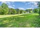 Spacious green yard surrounded by mature trees, offering a serene and private outdoor retreat at 120 Mossy Rock Trl, Iron Station, NC 28080