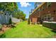 Backyard view of townhomes with green grass, brick walls, landscaping, and privacy fence at 12047 Lavinia Ln, Charlotte, NC 28277