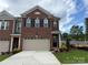 A charming brick townhome featuring a two-car garage and classic architectural details under a cloudy sky at 12047 Lavinia Ln, Charlotte, NC 28277
