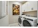 Laundry room with modern washer and dryer, white cabinets, and neutral wall art at 12051 Lavinia Ln, Charlotte, NC 28277
