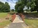 Community park with wooden bridge crossing over a stream, with large green trees and lawns at 13223 Willow Breeze Ln, Huntersville, NC 28078